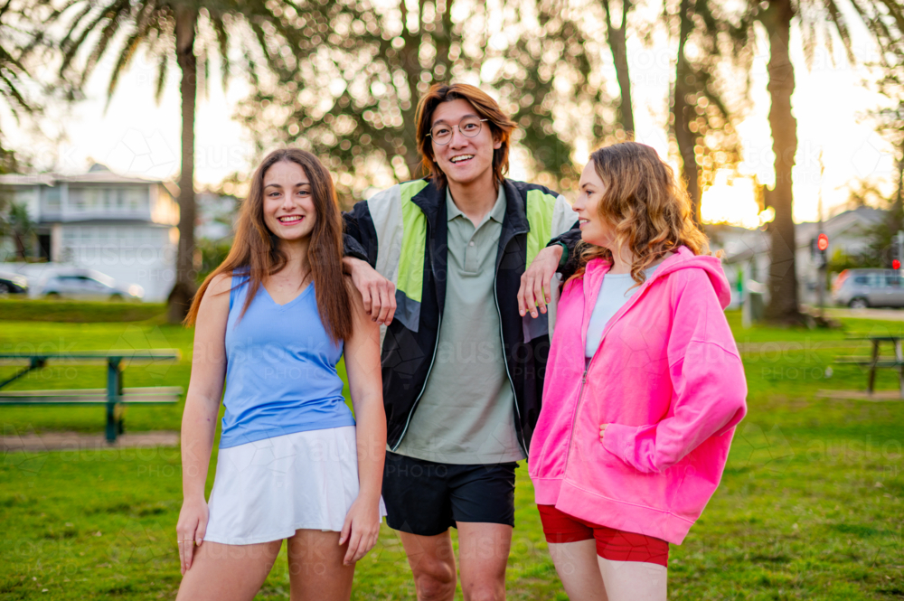 Group of young people socialising and having fun in a park on a warm evening - Australian Stock Image