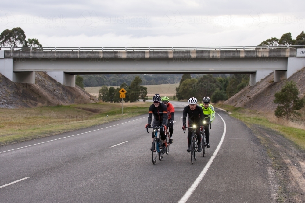 Groups of cyclists riding on a country road in the early morning - Australian Stock Image