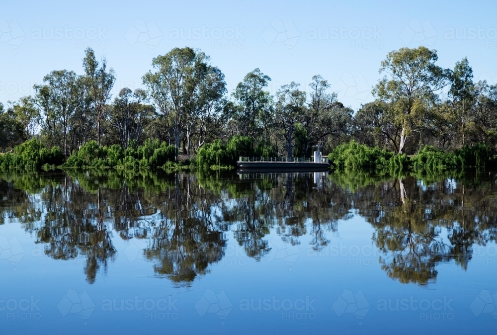 gum trees and barge reflected on still river - Australian Stock Image