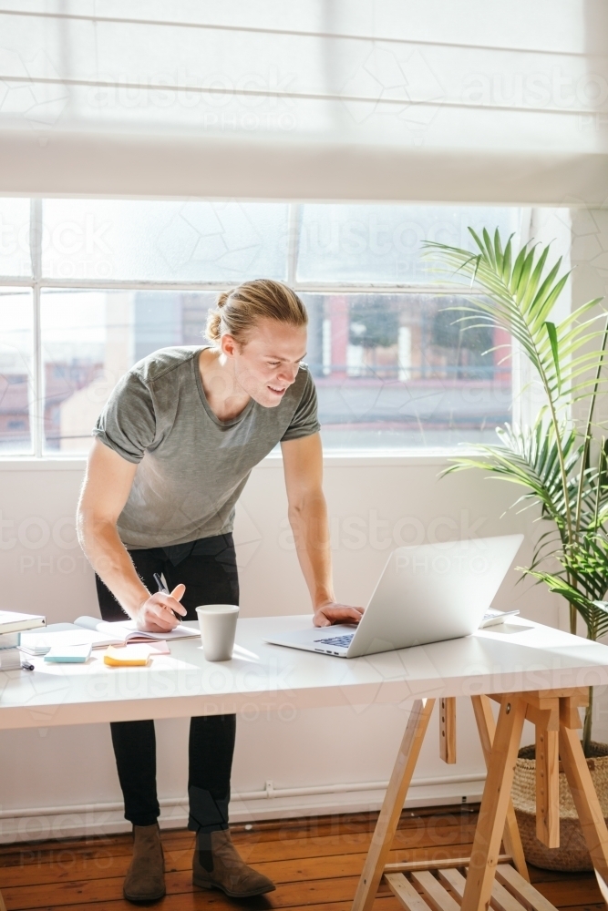 Guy in casual clothes working in a bright studio - Australian Stock Image