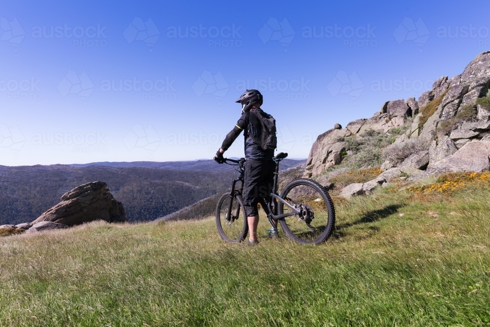 Guy looking at the view on a mountain bike at Thredbo in summer - Australian Stock Image
