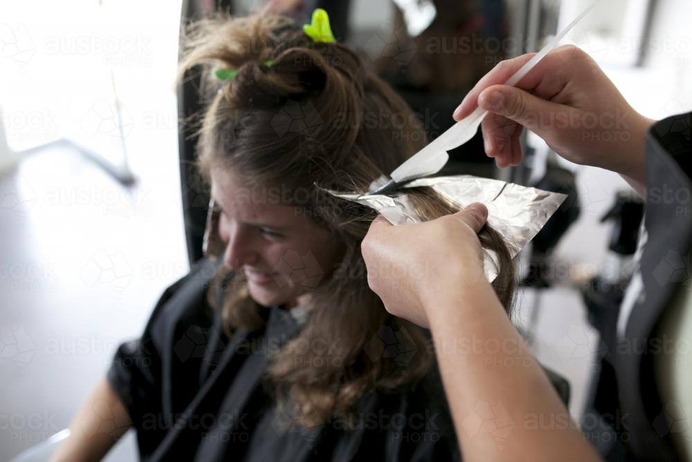 Hairdresser adding foils to a woman's hair - Australian Stock Image