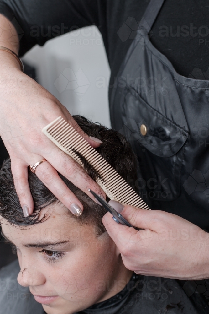 Hairdresser cutting teenage boys hair - Australian Stock Image