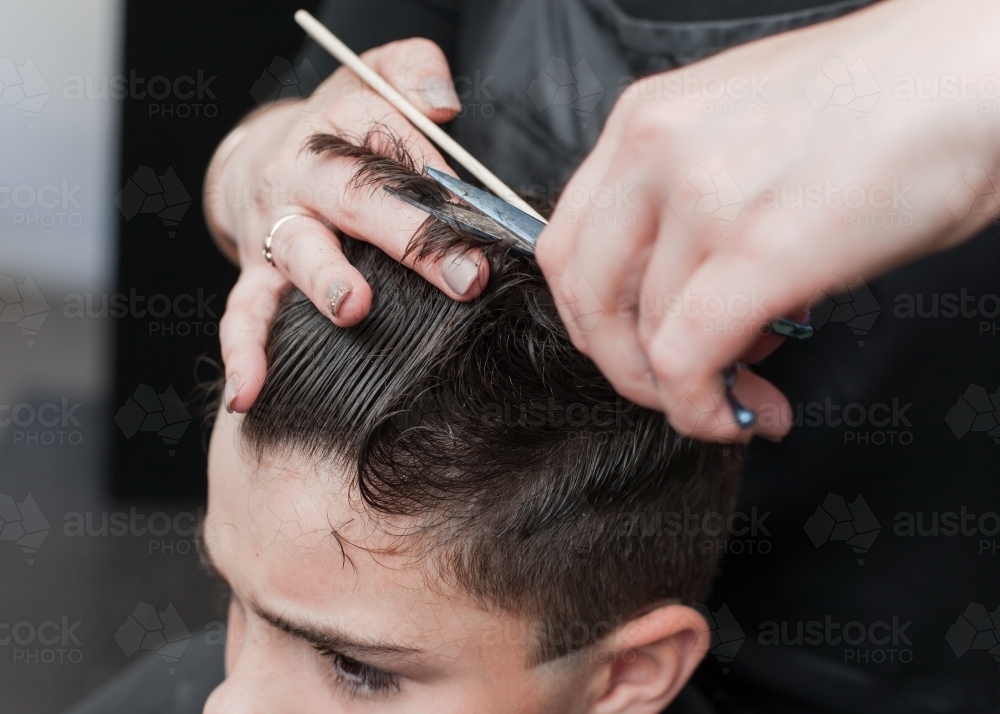 Hairdresser cutting teenage boys hair - Australian Stock Image