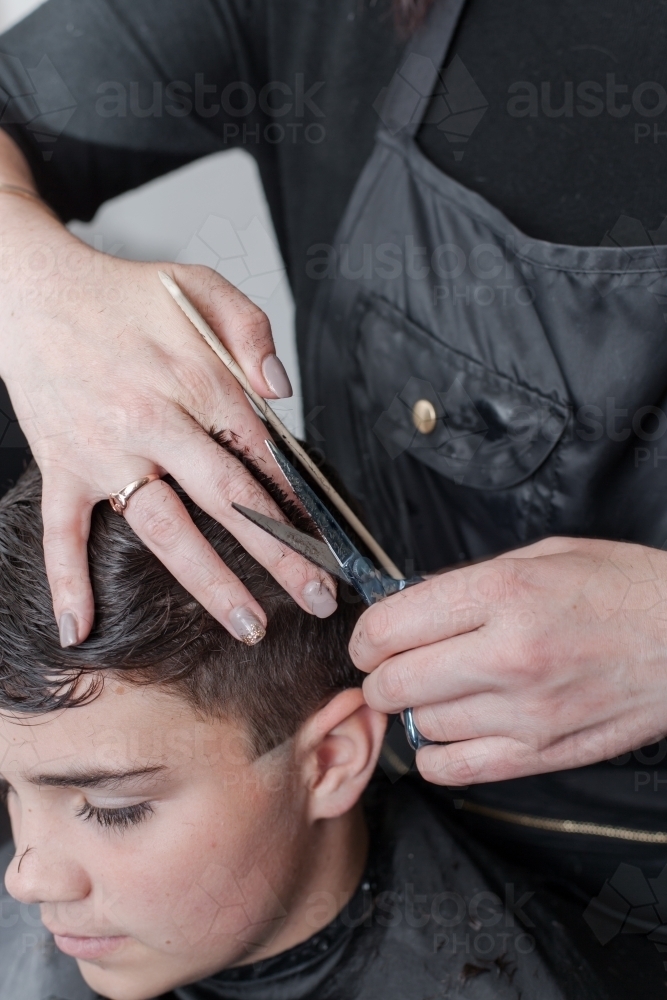 hairdresser cutting teenage boys hair - Australian Stock Image