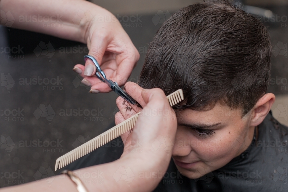 Hairdresser cutting teenage boys hair - Australian Stock Image