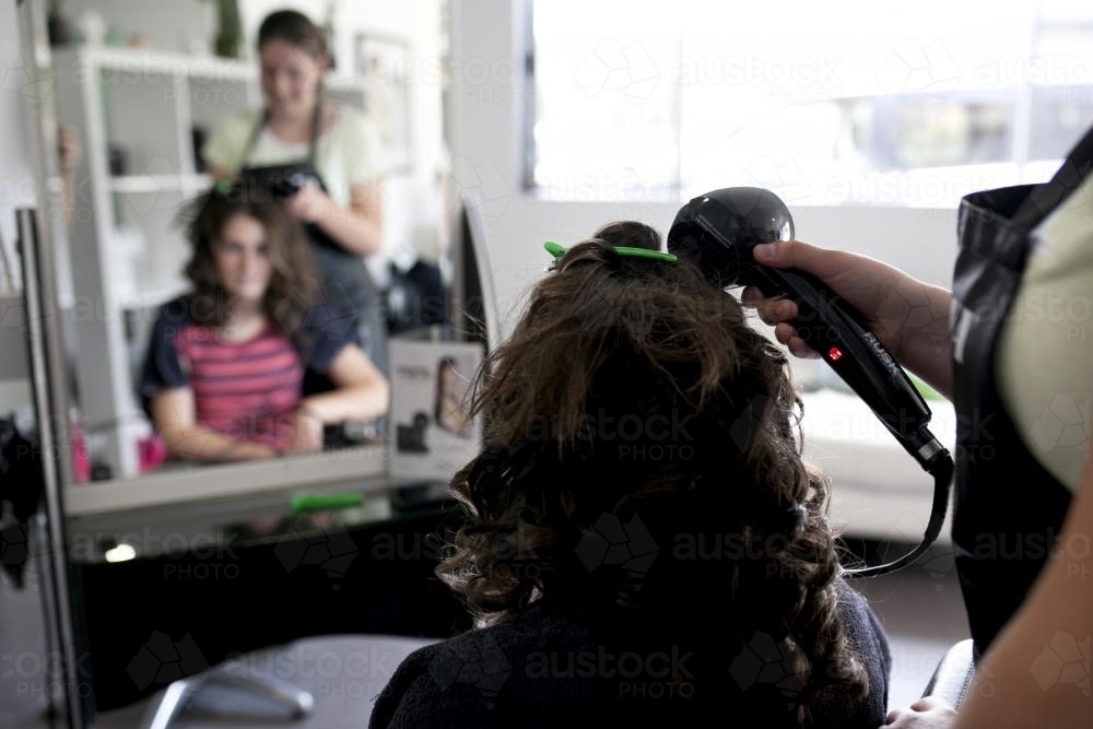 Hairdresser styling a young woman's hair - Australian Stock Image
