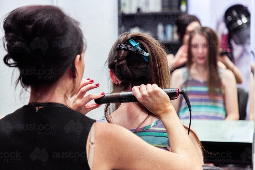 Hairdresser styling young clients hair in hair studio - Australian Stock Image