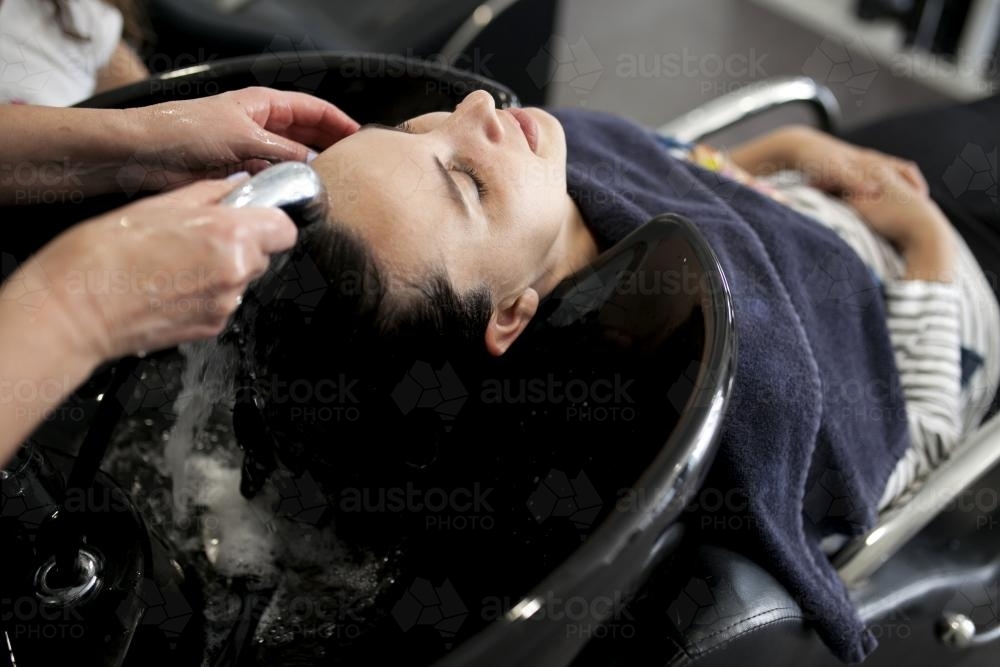 Hairdresser washing a woman's hair at a salon - Australian Stock Image