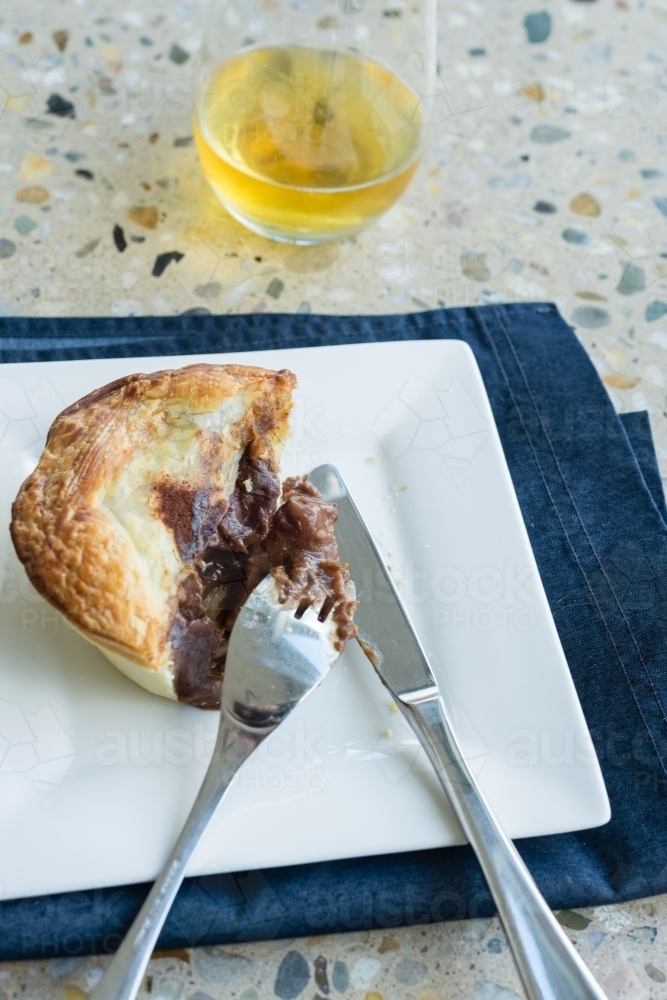 halfway through a meat pie, and beer - Australian Stock Image