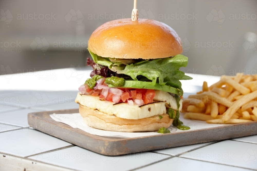 Haloumi burger on board with chips - Australian Stock Image