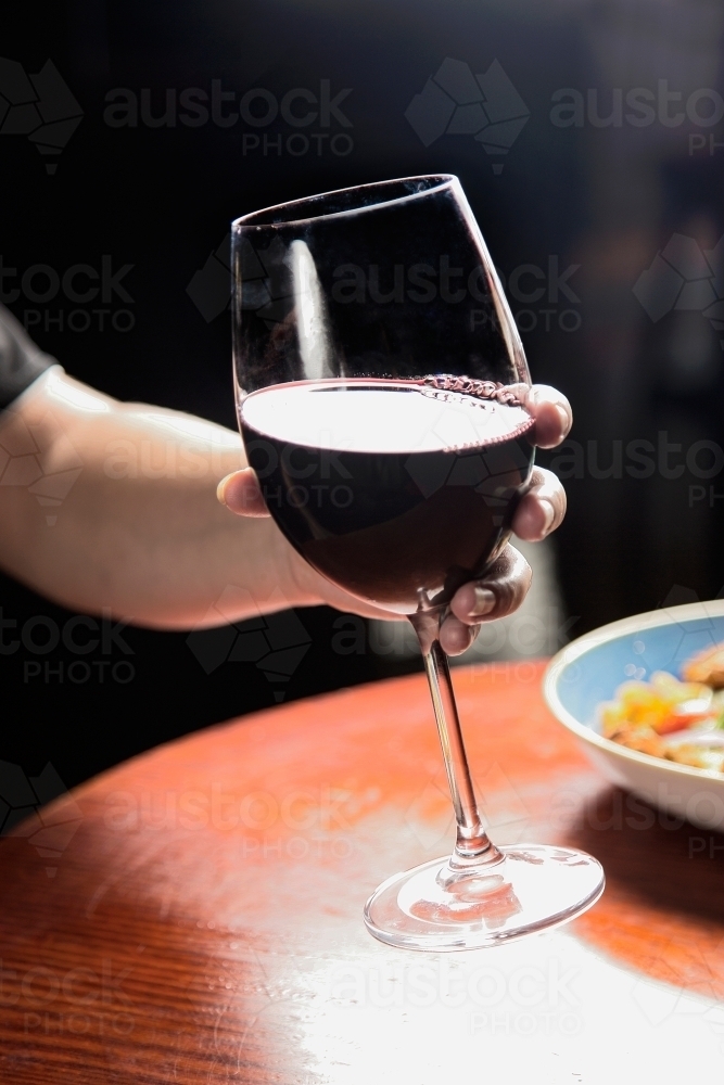 Image of Hand holding a glass of red wine - Austockphoto