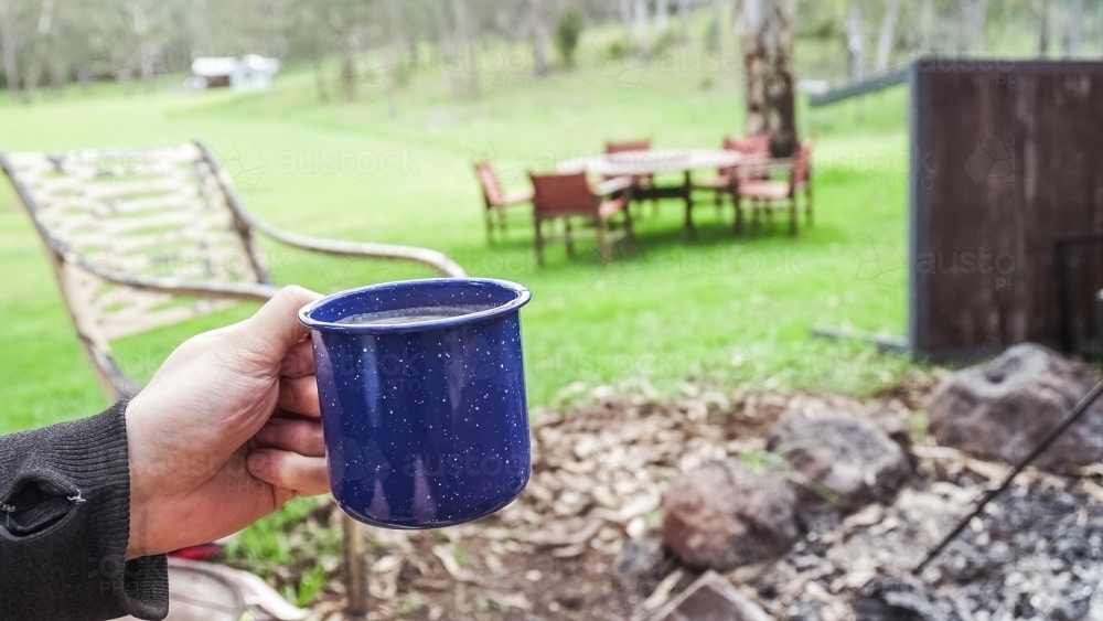 Hand holding camping coffee cup - Australian Stock Image