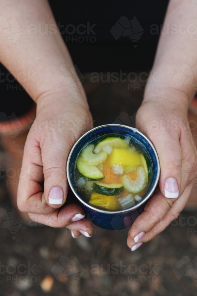 hand holding home made vegetable soup on a camping trip - Australian Stock Image