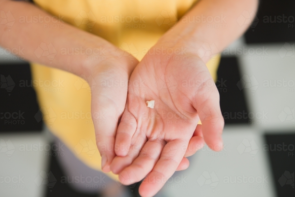 Hand of a child holding tooth that has fallen out - Australian Stock Image