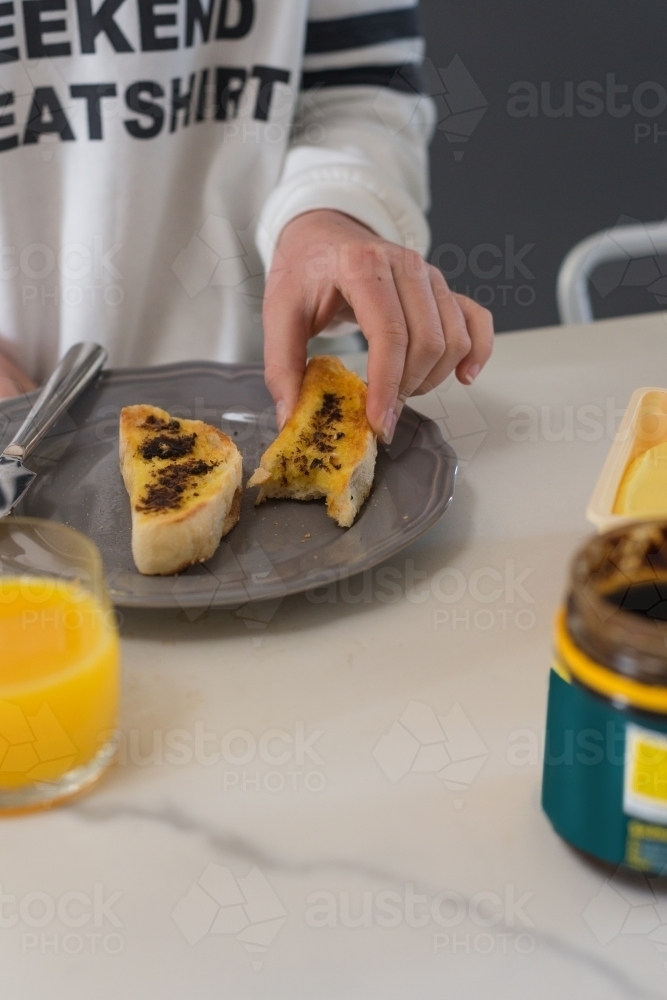 hand reaching for a piece of turkish toast with butter and vegemite - Australian Stock Image