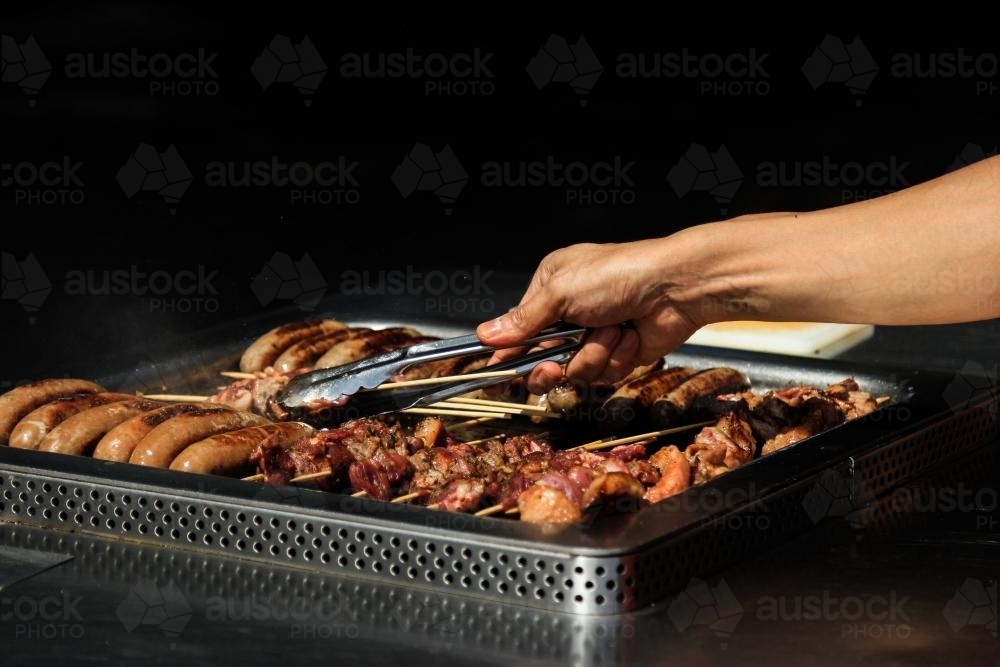 Hand turning kebabs on the BBQ - Australian Stock Image