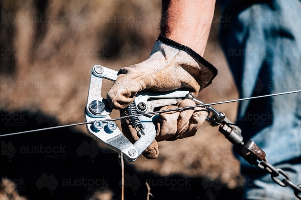Hand using strainer tool for fencing - Australian Stock Image