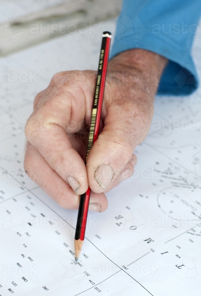 Hand with pencil marking sailing navigation points - Australian Stock Image