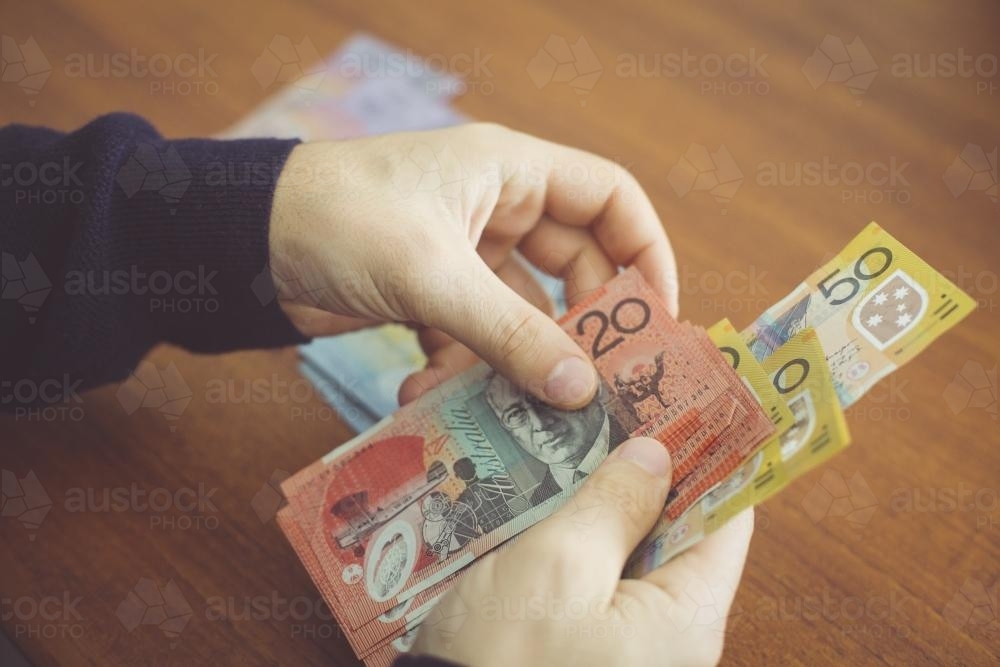 Hands counting money on the table - Australian Stock Image