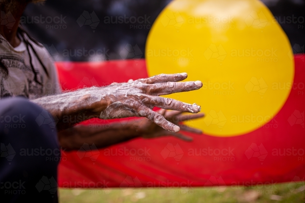 Hands covered in white paint in front of the Aboriginal Flag - Australian Stock Image