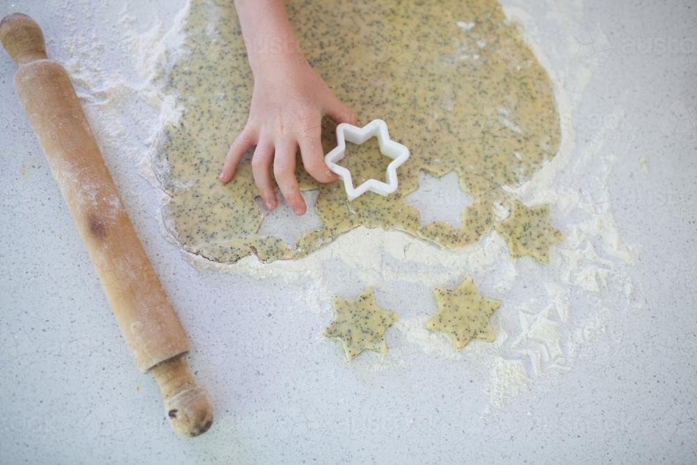 Hands cutting out biscuit dough - Australian Stock Image