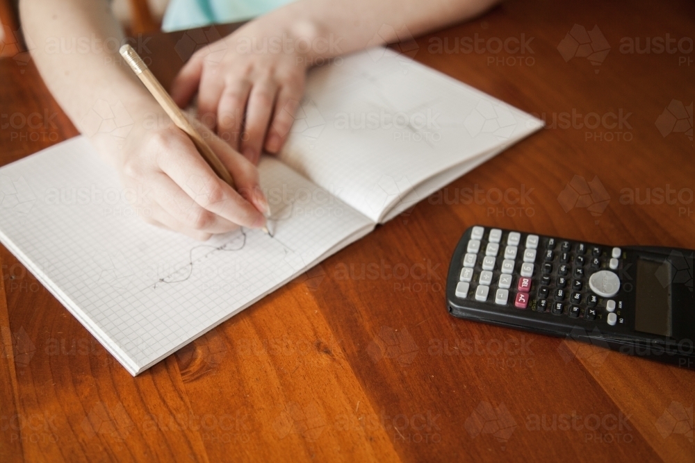 Image of Hands drawing out maths problem on graph paper - Austockphoto