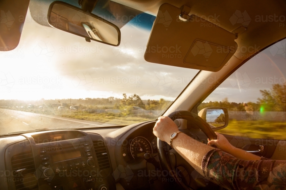 Hands driving car with sun flare on New England Highway - Australian Stock Image