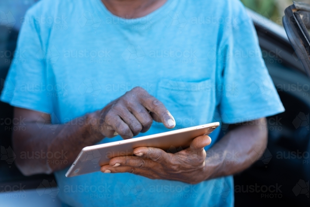hands holding a digital tablet and tapping screen - Australian Stock Image