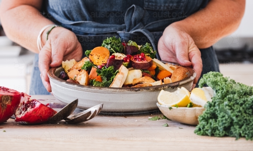 Image of Hands holding a salad bowl on kitchen bench. Austockphoto