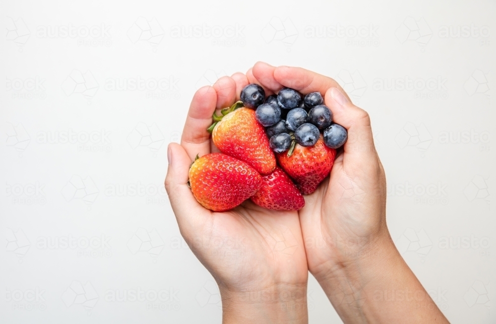 Hands holding blueberries and strawberries - Australian Stock Image