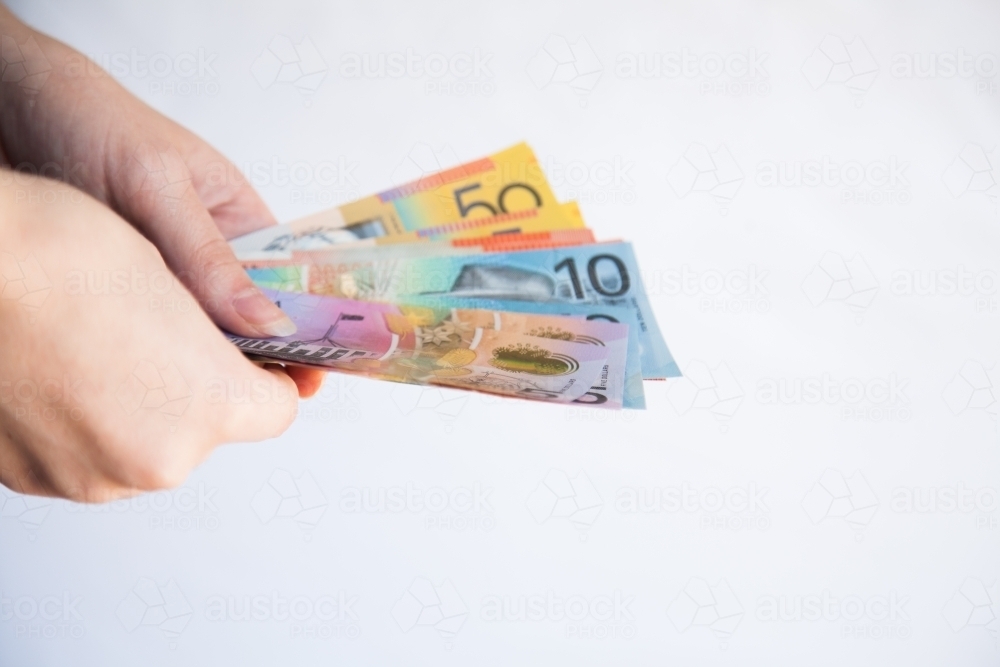 Hands holding notes of Australian money five, ten, twenty and fifty dollar notes - Australian Stock Image