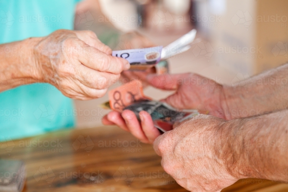 Hands of old person handing over money to a middle aged man - Australian Stock Image
