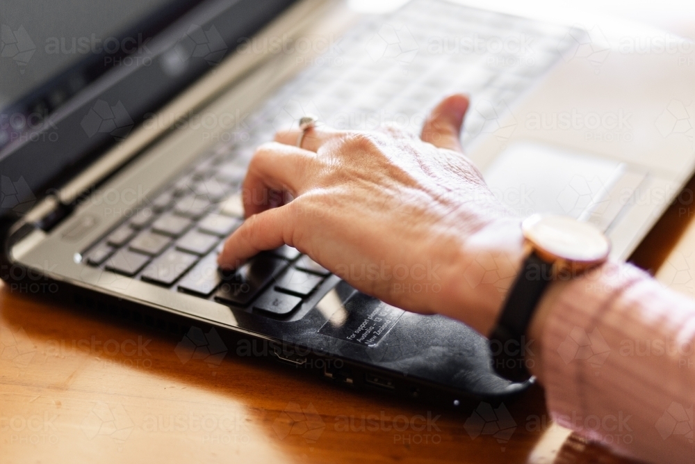 Hands of older woman typing on laptop - Australian Stock Image