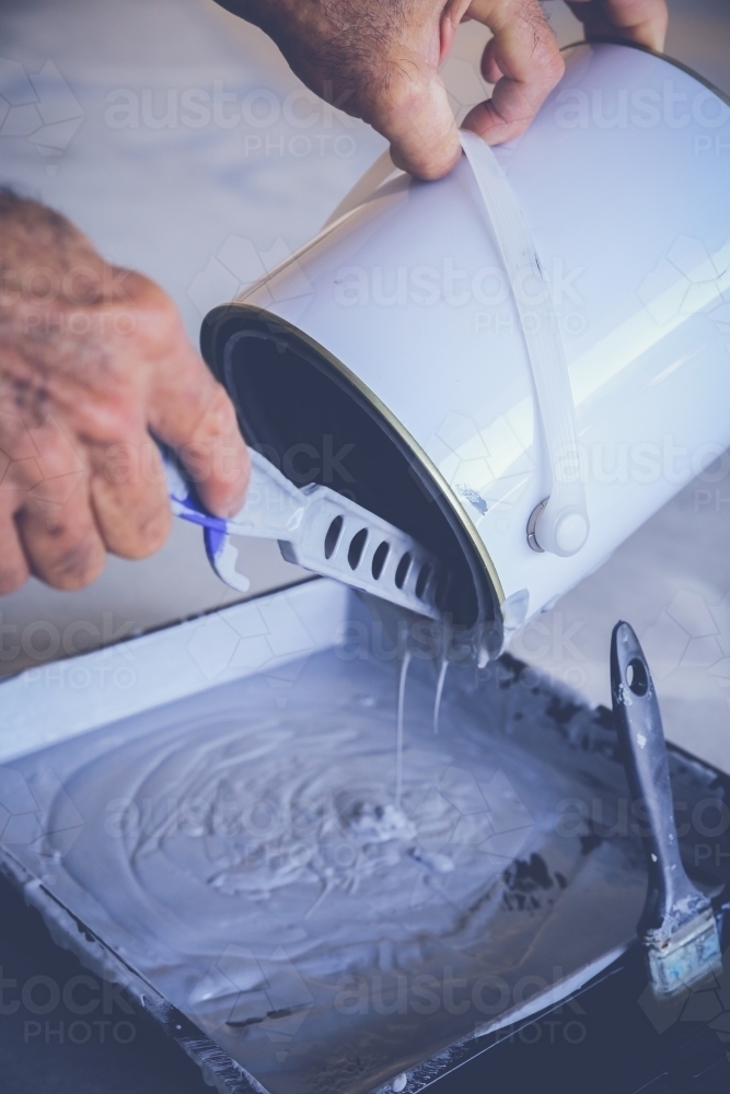 Hands pouring paint into tray - Australian Stock Image