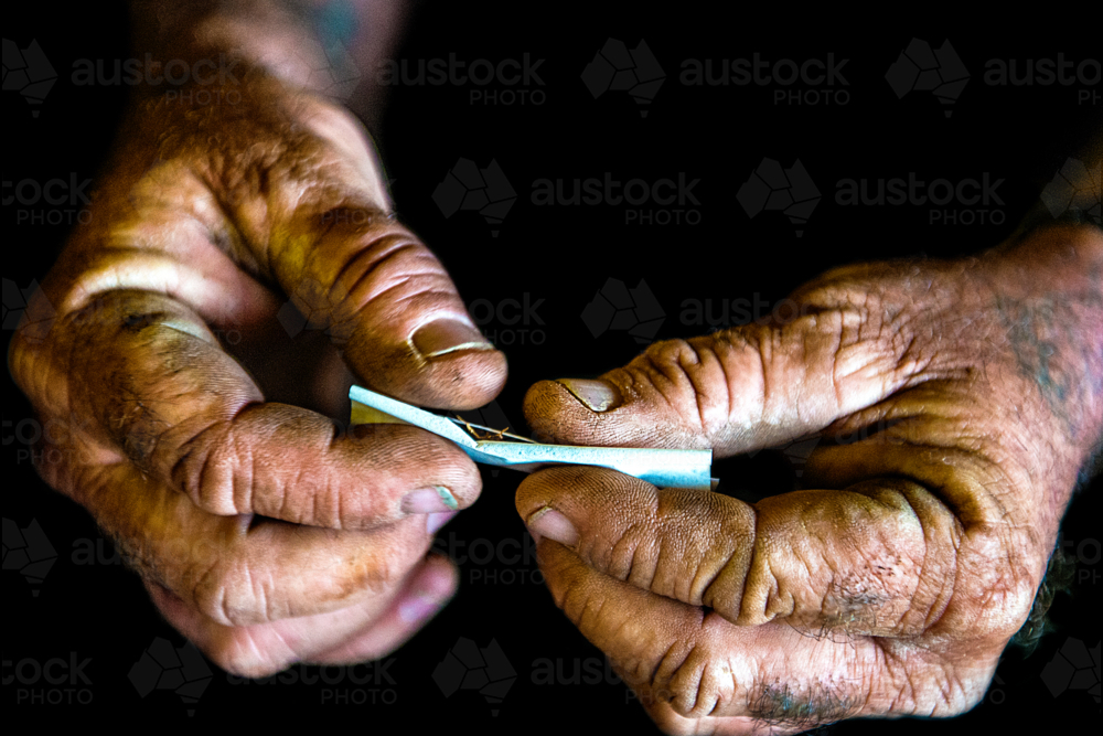 Hands rolling a cigarette with tobacco. - Australian Stock Image