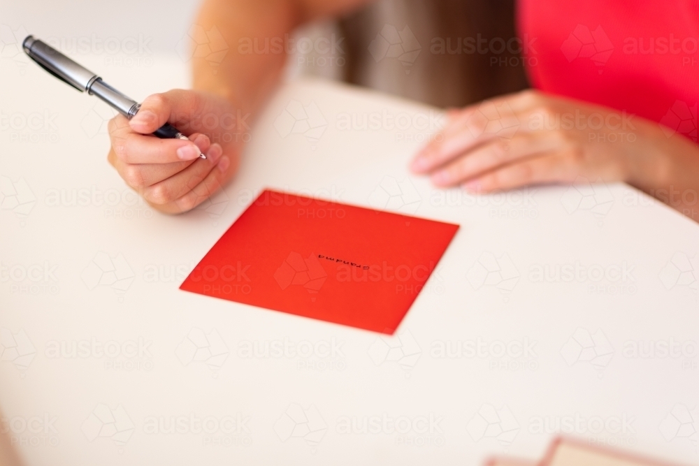 hands with pen and envelope with name written on it - Australian Stock Image
