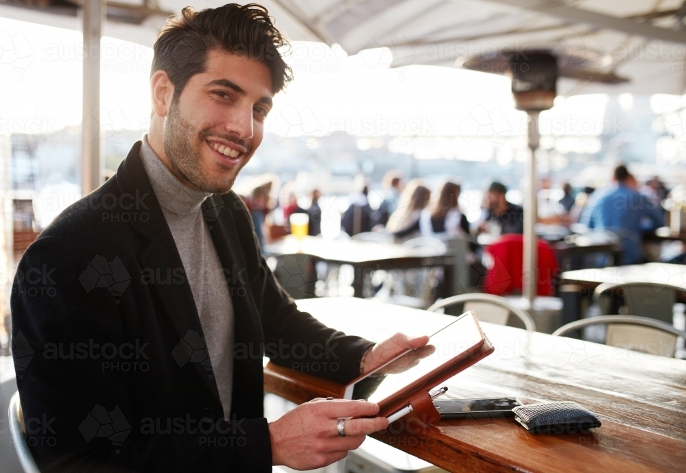 Handsome man using device at restaurant - Australian Stock Image