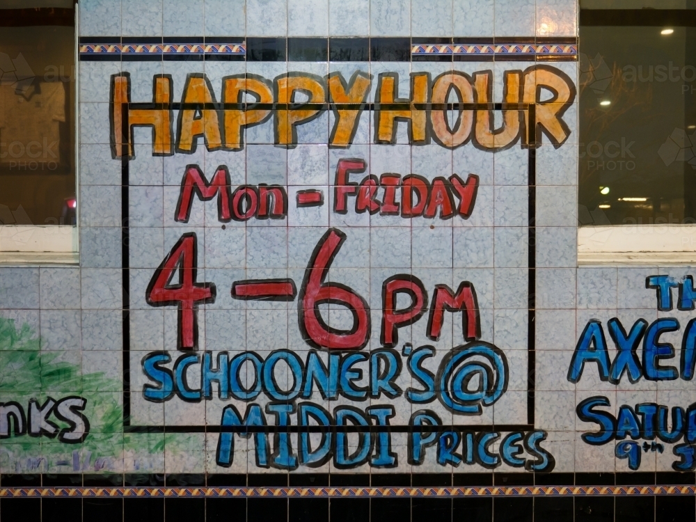Handwritten "Happy Hour" sign on tiles outside a pub - Australian Stock Image