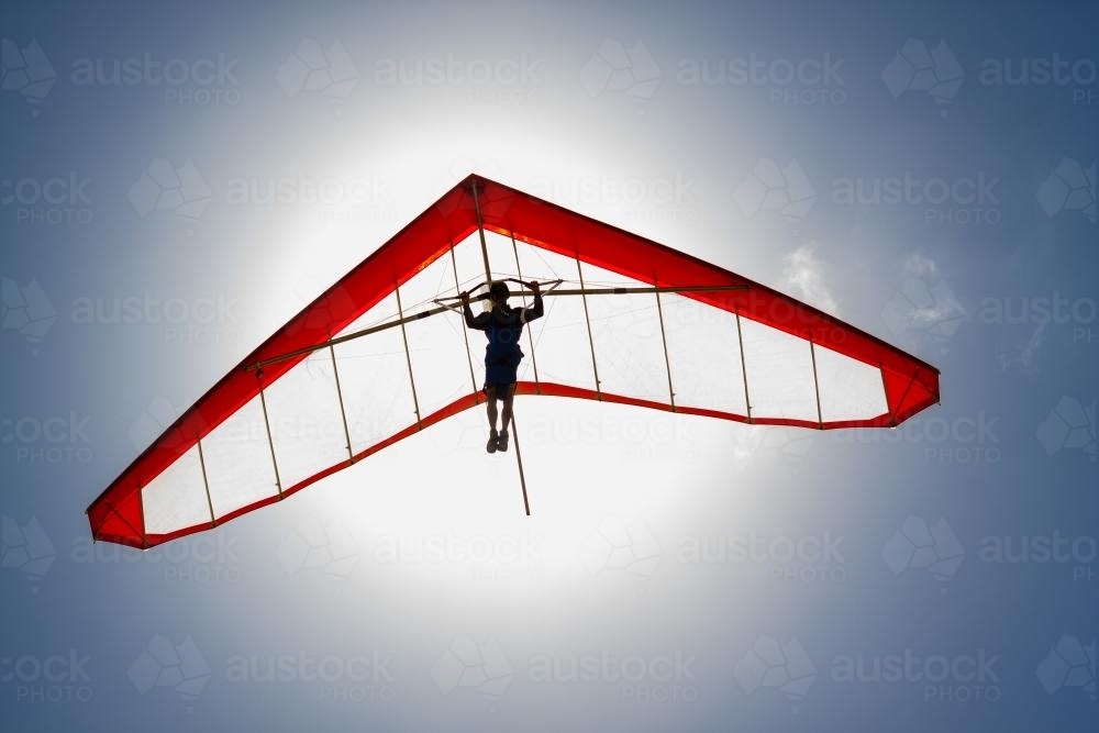 Hang glider soaring in front of the sun. - Australian Stock Image