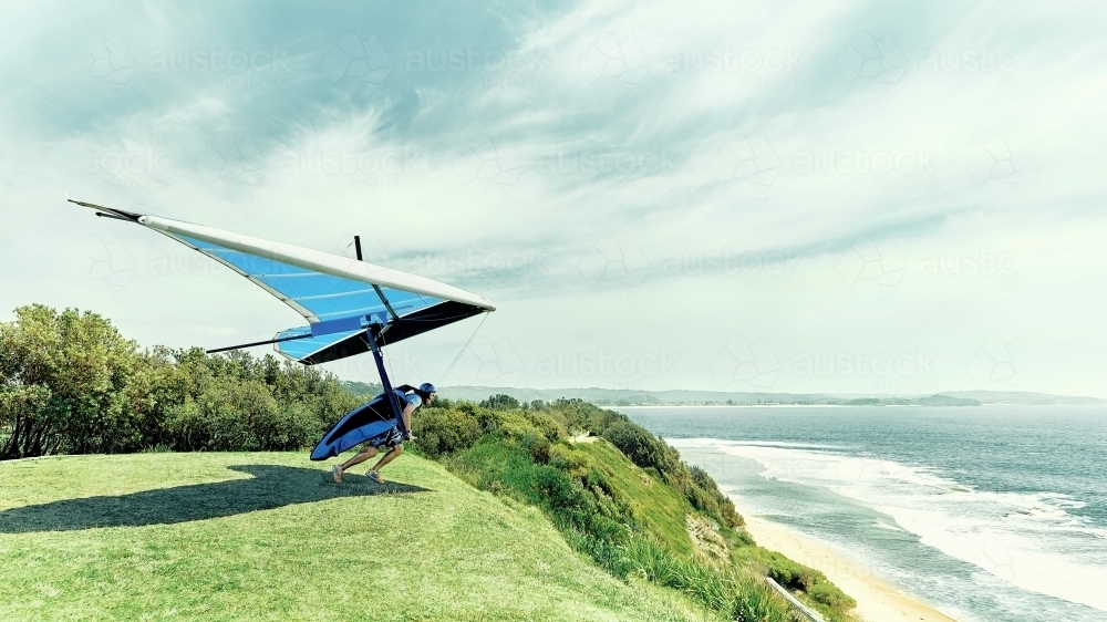 Hang glider taking off a cliff by the ocean - Australian Stock Image