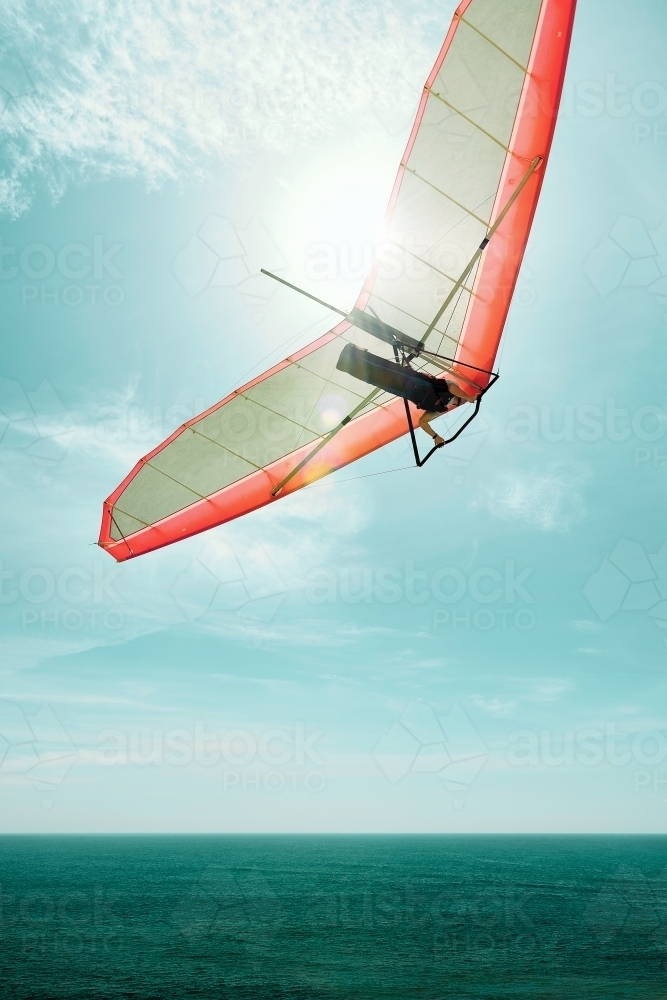Hang gliding into the sun with a red glider - Australian Stock Image