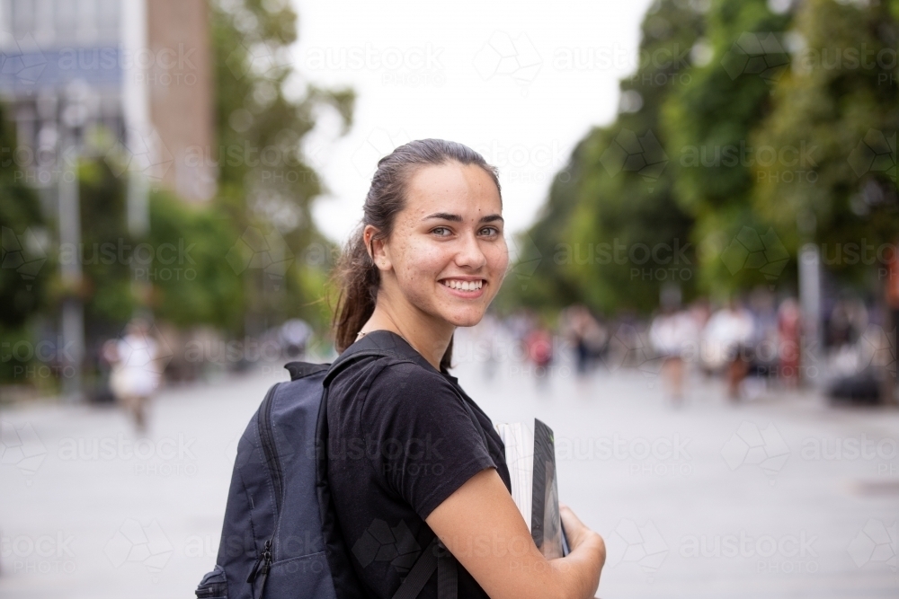 Happy aboriginal female university student holding textbooks  - Australian Stock Image