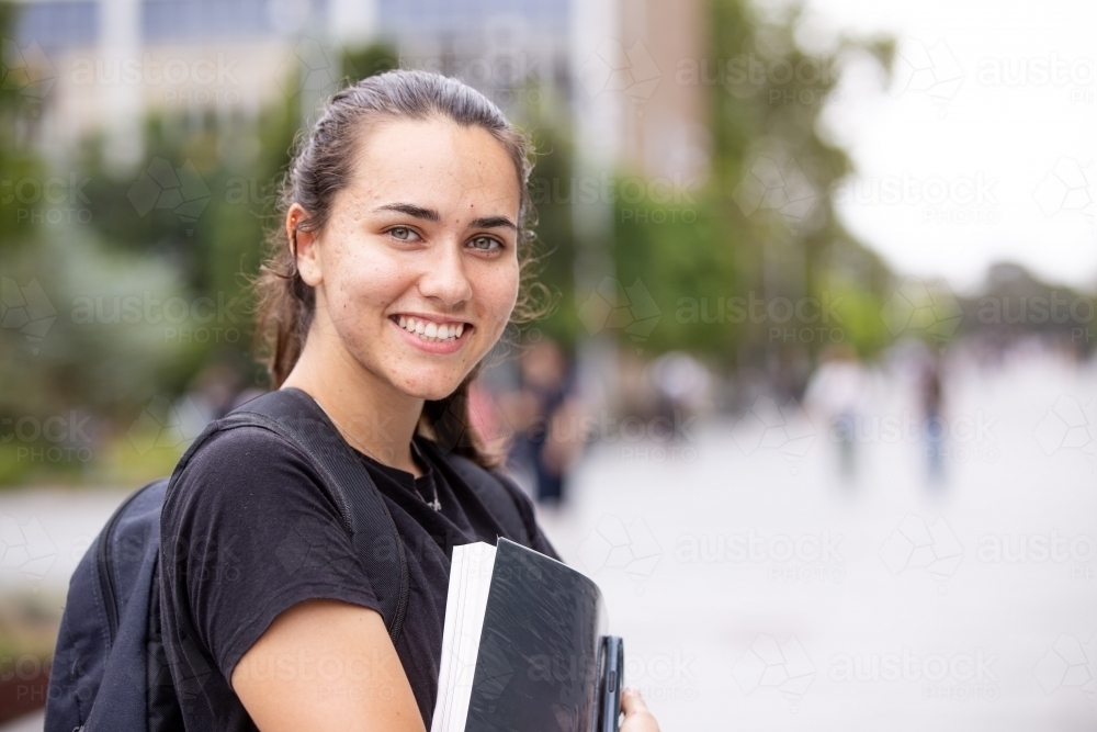 Happy aboriginal female university student holding textbooks  - Australian Stock Image