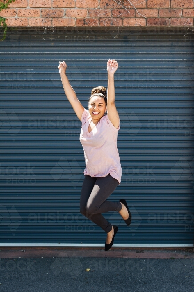happy aboriginal woman jumping - Australian Stock Image