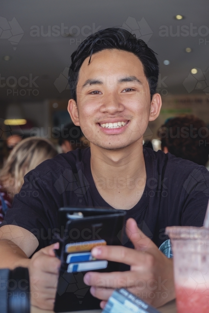 Happy Asain teen boy in juice bar - Australian Stock Image
