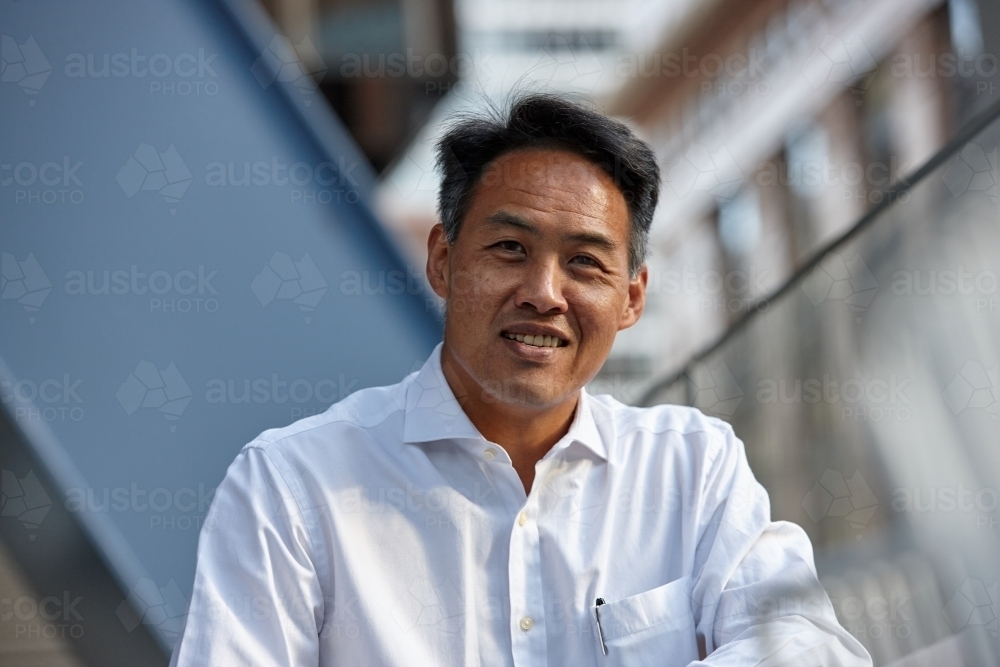 Happy Asian business man wearing open collar shirt - Australian Stock Image