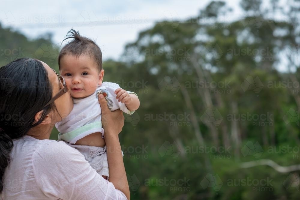 Happy Asian mum with her mixed race baby boy outside - Australian Stock Image