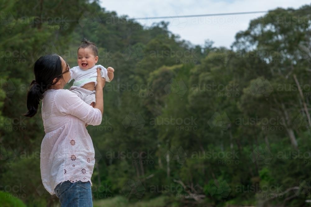 Happy Asian mum with her mixed race baby boy outside - Australian Stock Image