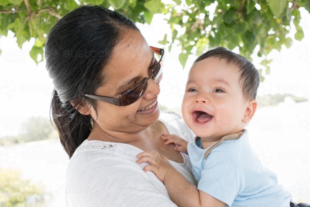 Happy Asian mum with her mixed race baby boy outside - Australian Stock Image